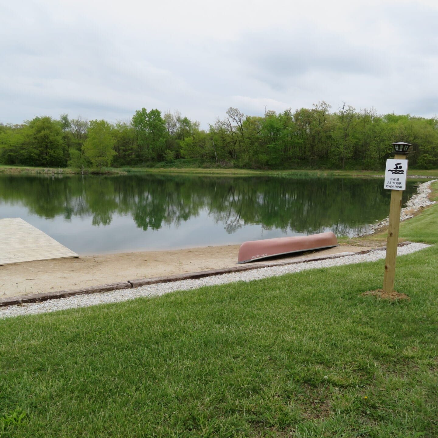 A boat is parked on the grass near a lake.